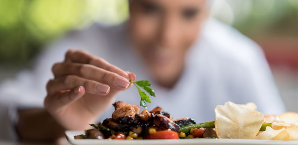 Close-up on a chef decorating a plate with a focus on the food restaurant concepts. 