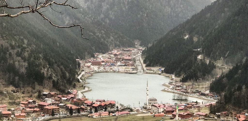 A city and a lake in the middle of a beautiful and lush mountain. 

