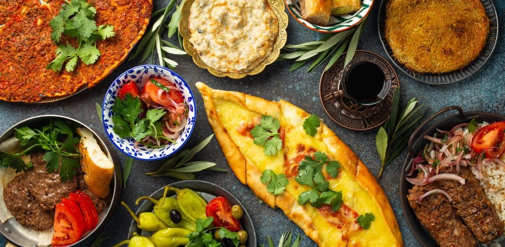 Traditional Turkish food, assorted dish and mezze appetizer on rustic background from above. Pide, Lahmacun, meat kebab, Turkish meatballs, sweet baklava and Kunefe.  Top view. 