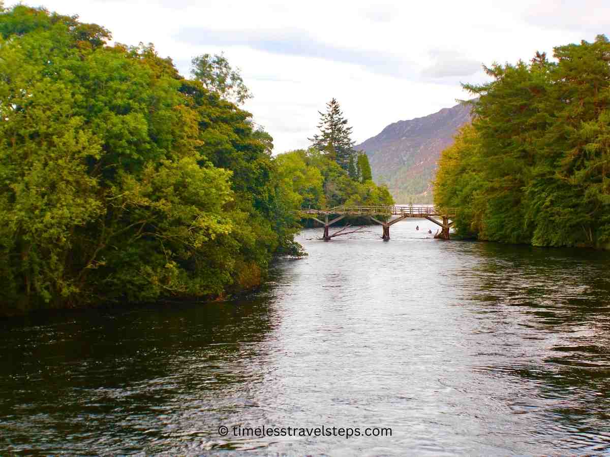 the remains of an old bridge across River Oich by Loch Ness, Scottish Highland with views of the trees along the water's edge slowly changing to golden yellow, adding a layer of beauty and evoking a sense of tranquility.