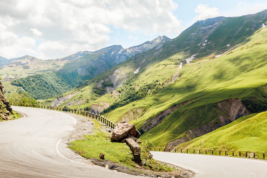 Green mountains surround a mountain road from Tbilisi to Gudauri in the Greater Caucasus mountains of Georgia.