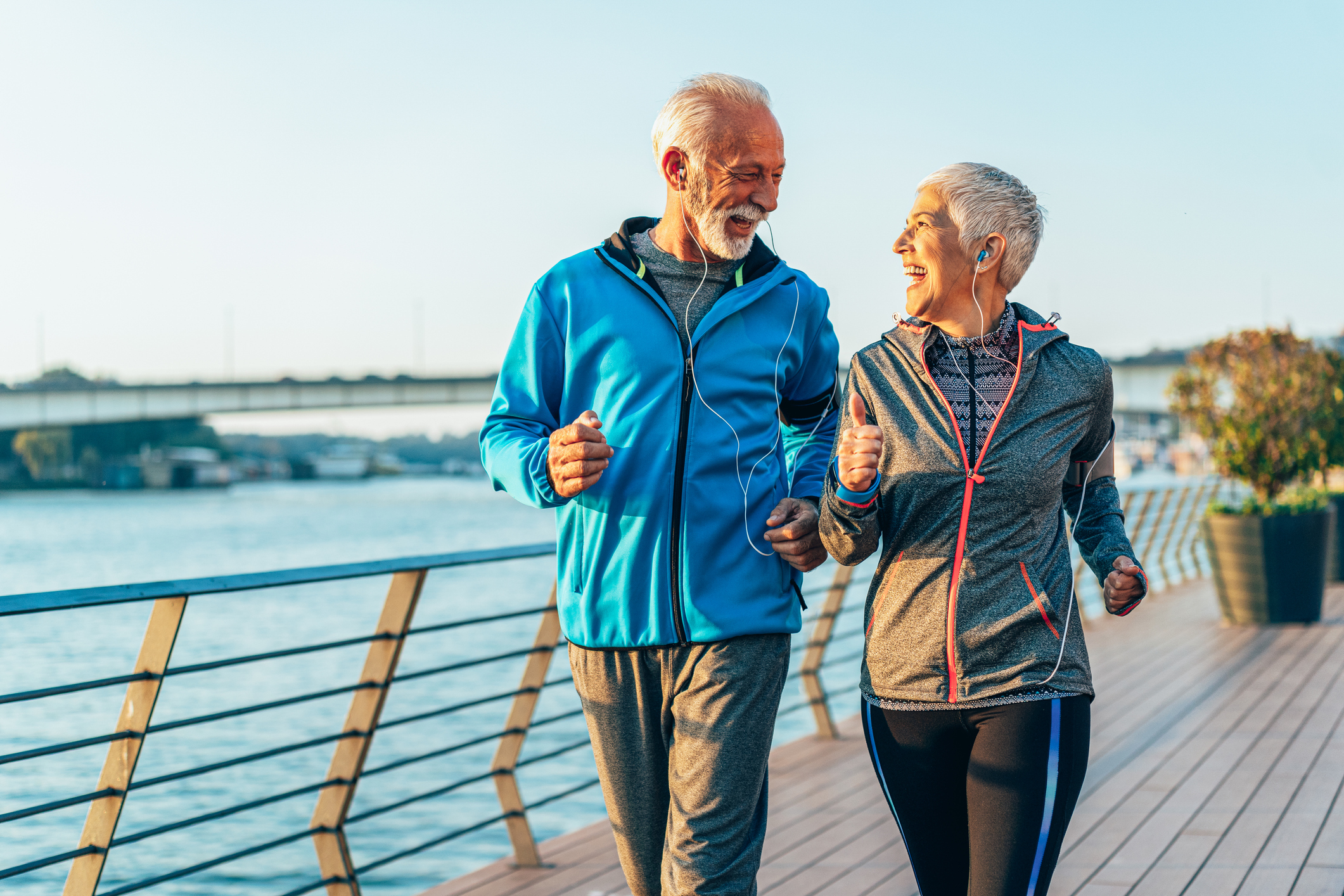 Two smiling people walking along a waterfront.