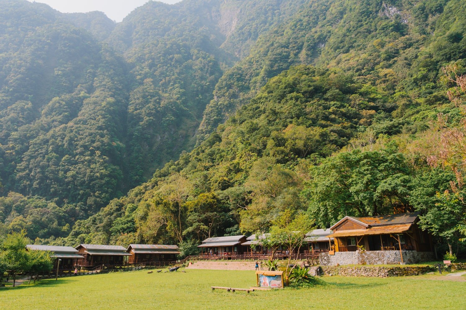 Panoramic view of the Taroko Village Hotel grounds with individual chalets at the base of forested mountains.