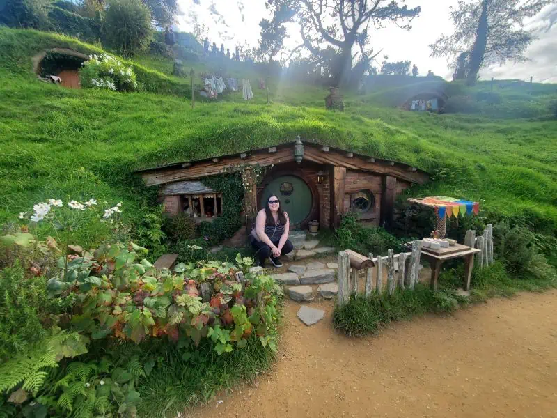 Riana of Teaspoon of Adventure in front of a Hobbit Hole in Hobbiton, New Zealand