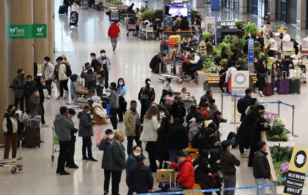 A traveler passes by a flight information display board at Incheon International Airport, Dec. 7. Yonhap