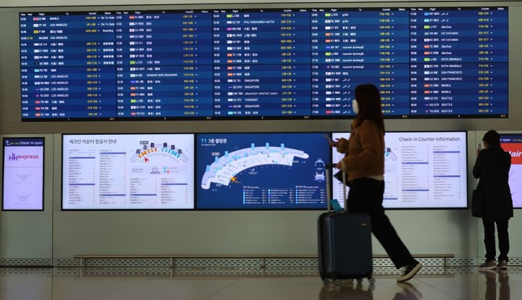 A traveler passes by a flight information display board at Incheon International Airport, Dec. 7. Yonhap