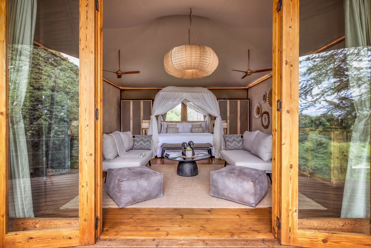 A room at the JW Marriott Masai Mara Safari Lodge in Kenya that has a bed with white netting, and plush sofas and cushions for lounging