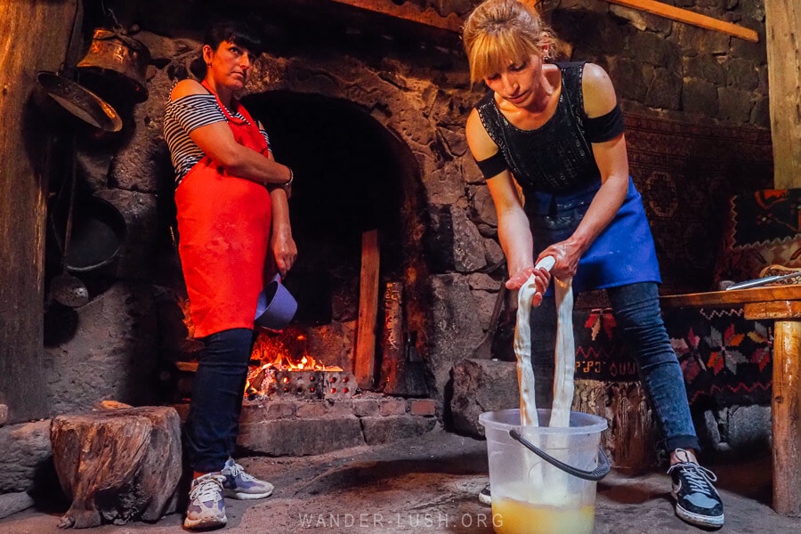 Two women making tenili pulled cheese in front of an open fire in a house in Meskheti region.