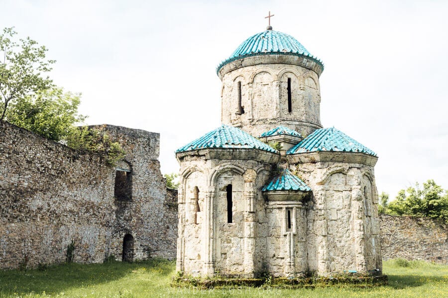 Kvetera Fortress's Church, a small stone chapel with a turquoise roof surrounded by a fortified stone wall in Georgia.