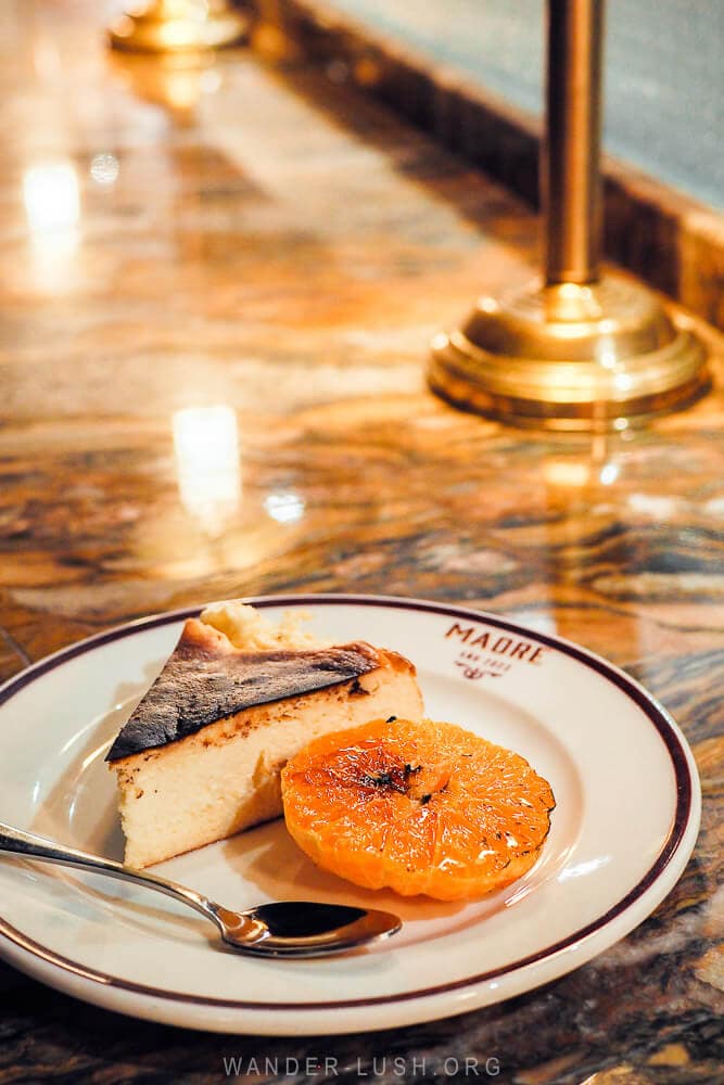 A slice of Basque cheesecake with a grilled mandarine on a marble table at a restaurant in Tbilisi.