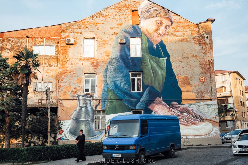 With Love by Sasha Korban, a street art mural in Kutaisi, Georgia depicting a woman in a headscarf preparing khachapuri.