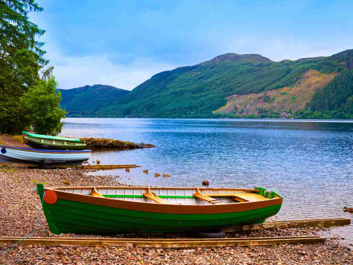 colourful boats on Dores beach, Loch Ness shoreline with mountains rising above across the loch