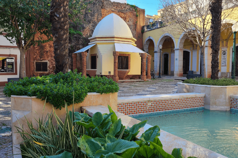 Praça do Município in Silves. The town square with islamic influenced smal building, red walls, and a blue fountain