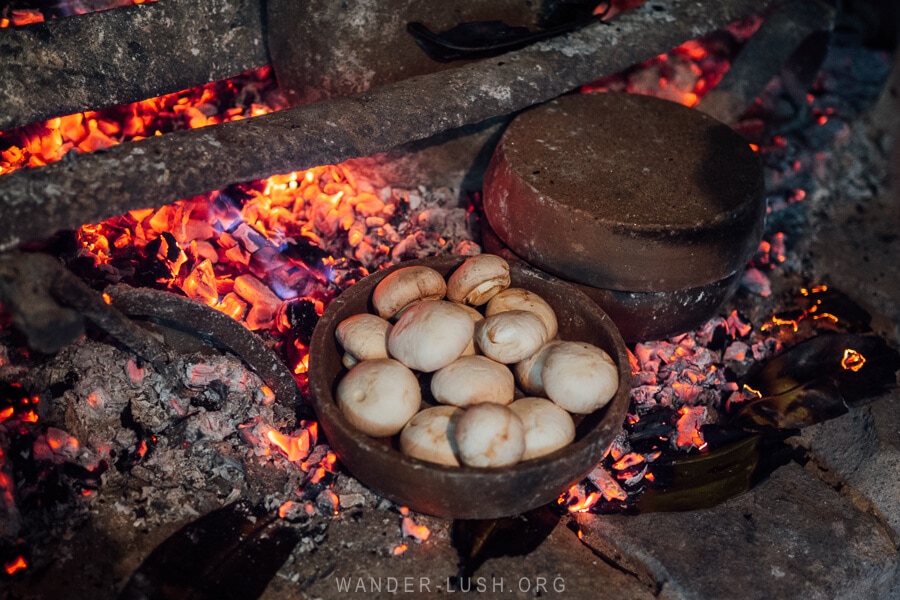 Mushrooms cooking in clay pan over an open fire, a traditional cooking technique in Imereti, Georgia.