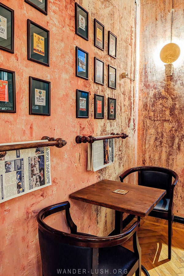 Sapere, a vintage wine bar and restaurant in Kutaisi with pink walls and framed cognac labels on the walls.