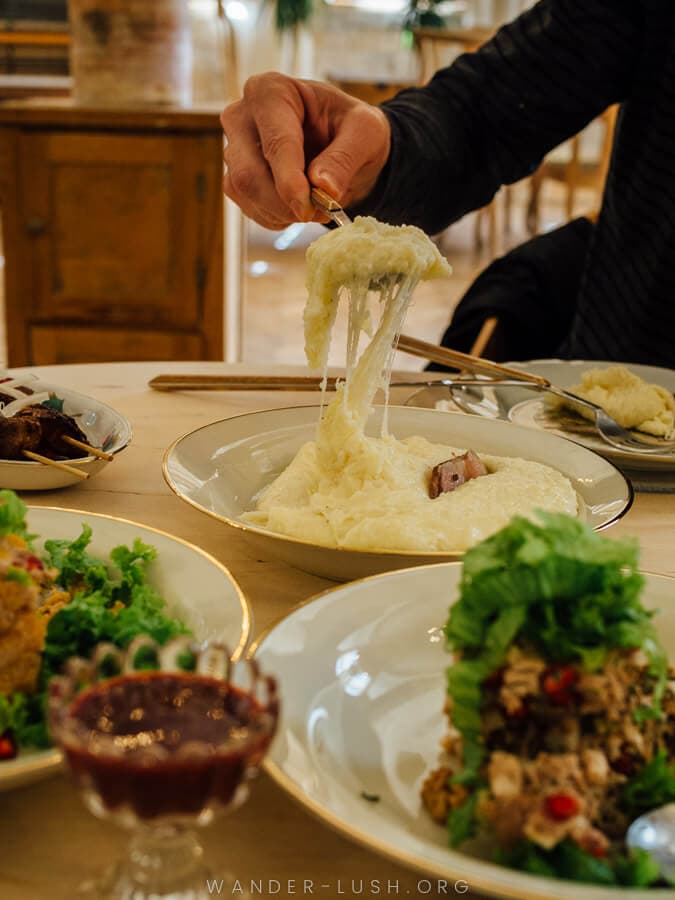 A man serves up cheesy elarji at a restaurant in Georgia.