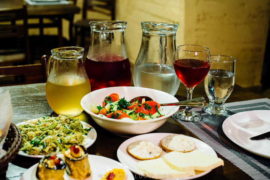 A spread of wine, cheese, bread and salad on a table.