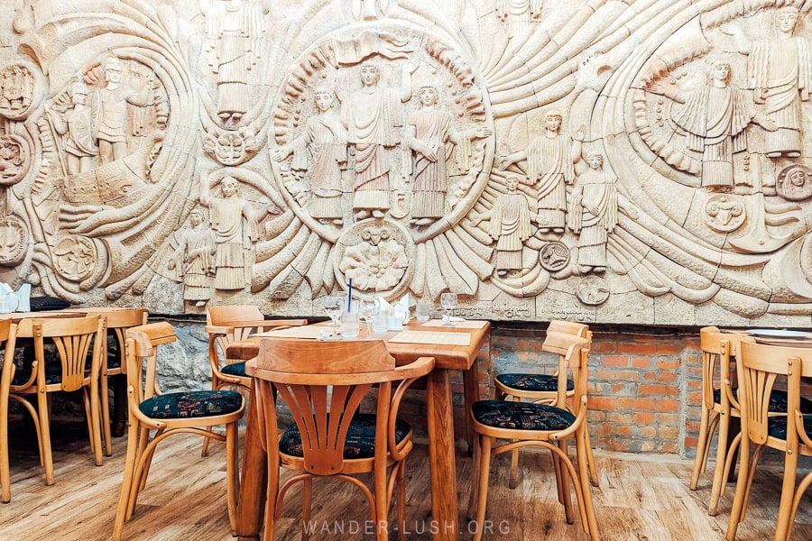 Tables set up in front of a wall of Soviet-era decorations at Argonauts Restaurant in Kutaisi, Georgia.