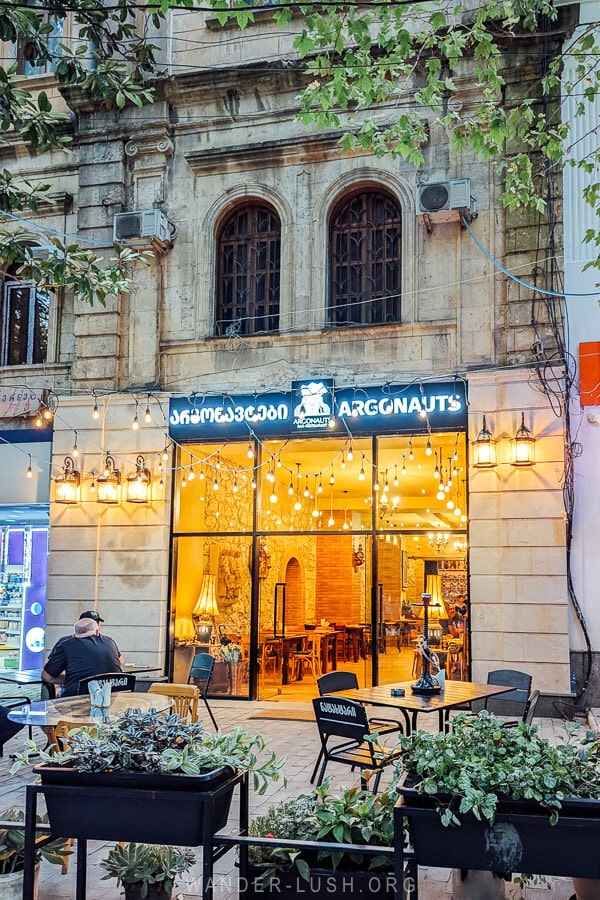 The facade of Restaurant Argonauts lit up at night in Kutaisi.