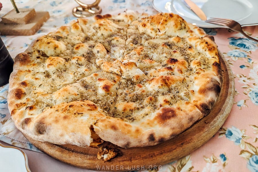 A big garlic bread pizza on a wooden board at an Italian restaurant in Kutaisi, Georgia.