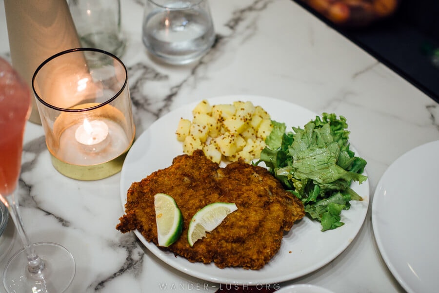 A plate of crumbed schnitzel on a white marble table.