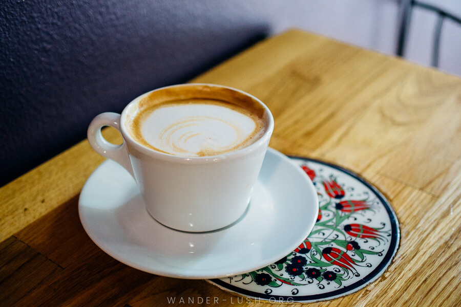 A cup of coffee sitting on a wooden table.