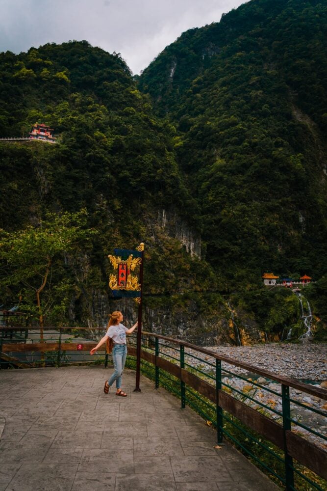 Female standing by a lamp pole overlooking the Eternal Spring Shrine & Bell Tower attraction in Taroko Gorge, Taiwan.