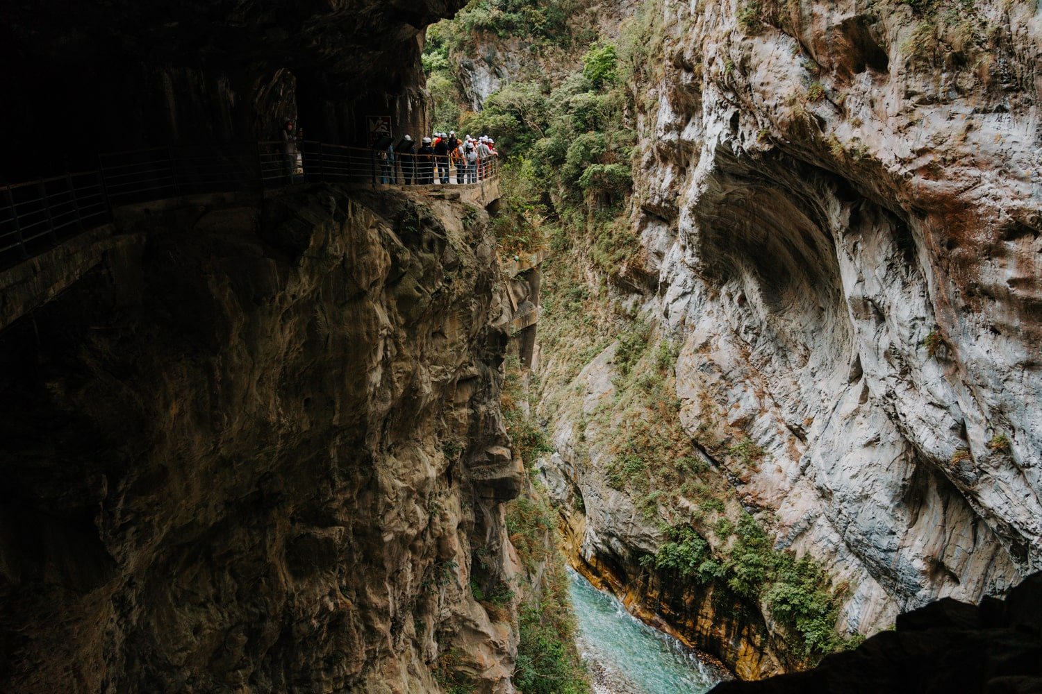 Tourists wearing hard-hats overlooking the canyon walls of Taroko Gorge on the Swallow Grotto Trail in Taroko National Park, Taiwan.