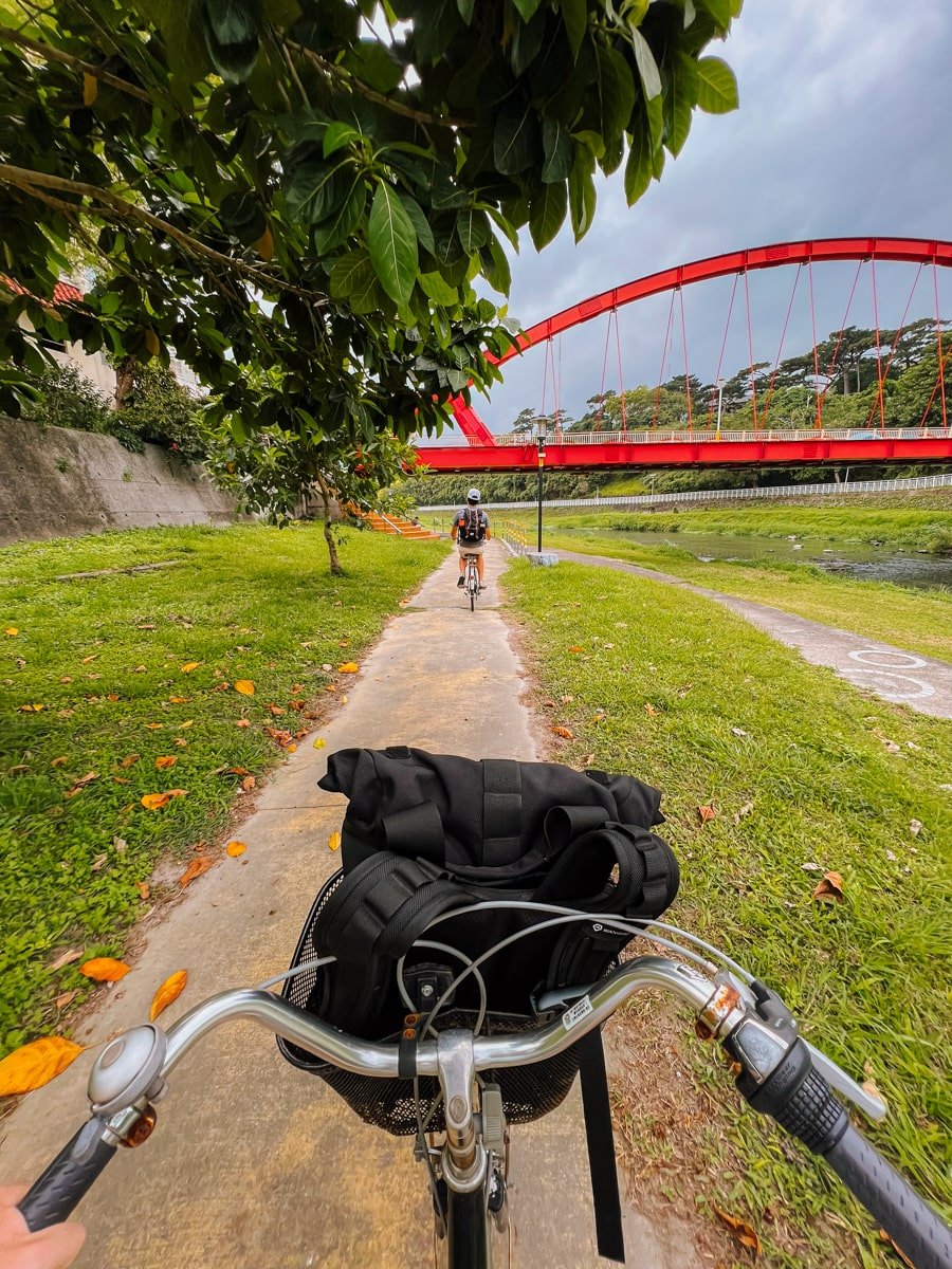 Biking along a bike path in Hualien with the red Jinguang Bridge in the background, Hualien Taiwan.