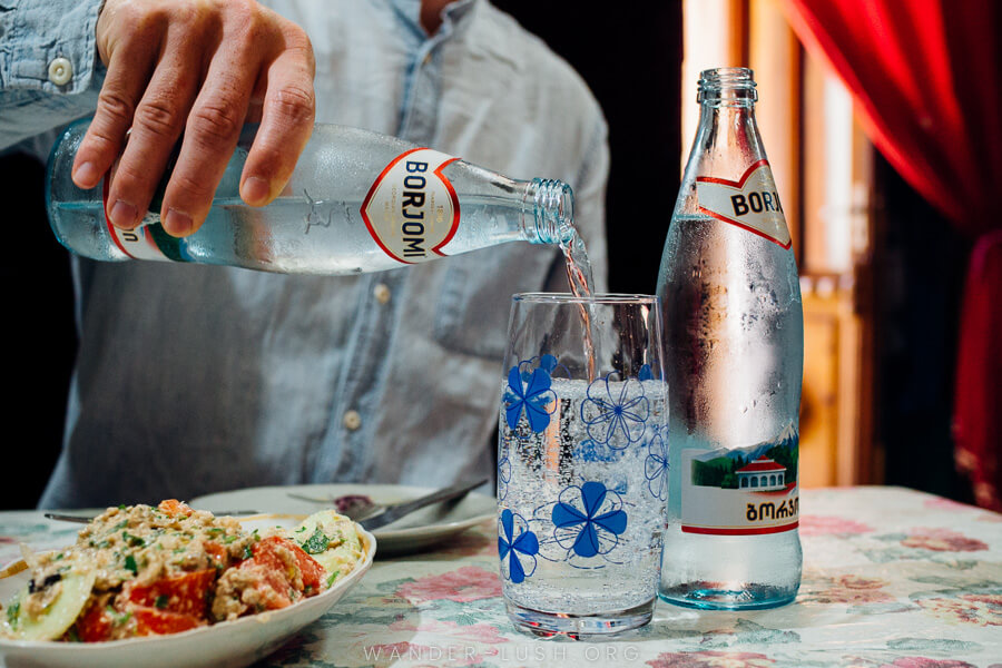 A man pours mineral water into a glass at a restaurant in Borjomi, Georgia.