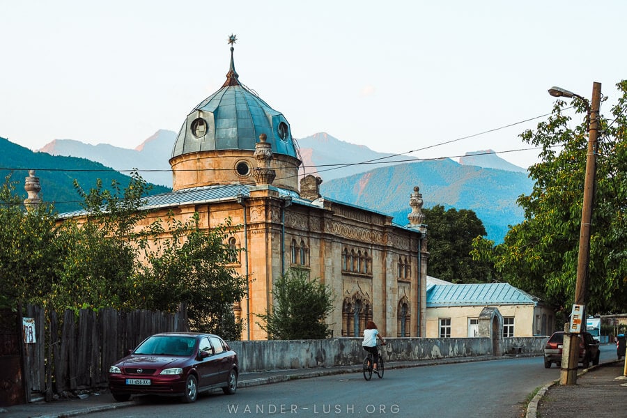 A woman rides a bicycle past Oni Synagogue in Oni, Racha.