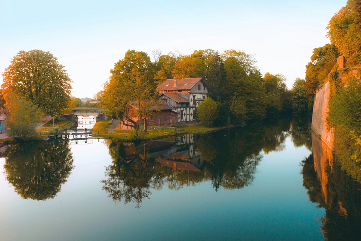 A home surrounded by lush green trees along the river in Metz, France. 