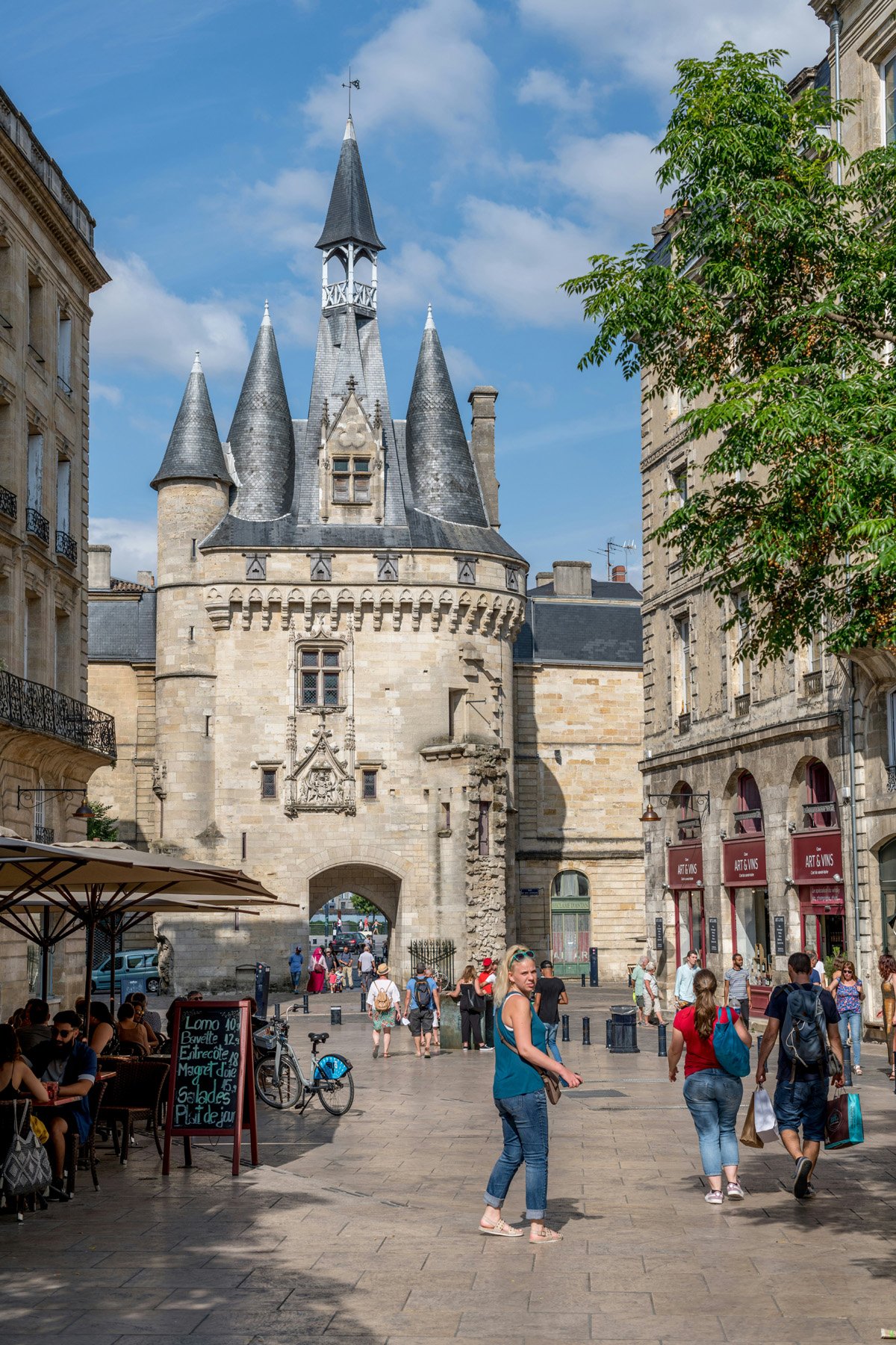 A charming old city gate in Bordeaux and a crowded street in midday. 