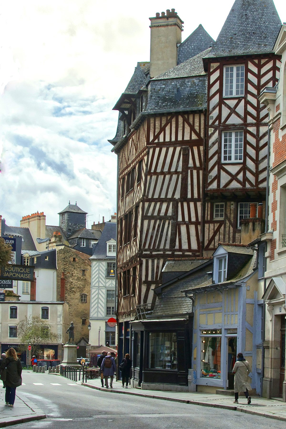 A narrow street in Rennes, France, with a tall half-timber house in the foreground. 