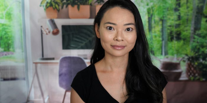 mia pham wears a black shirt and sits in a room with greenery behind her