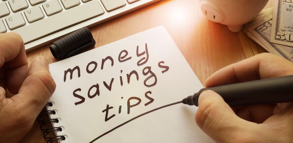 Savings advice is written in a note.  On the side are some cash, a pig toy, and a keyboard.

