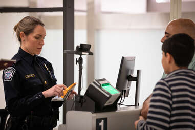 female officer checking a father and son's paperwork at airport