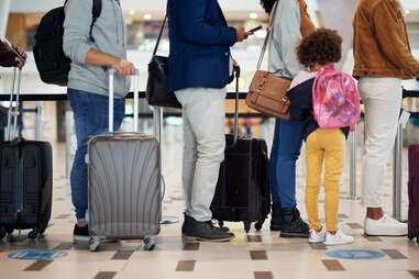 people waiting in line with suitcases at airport