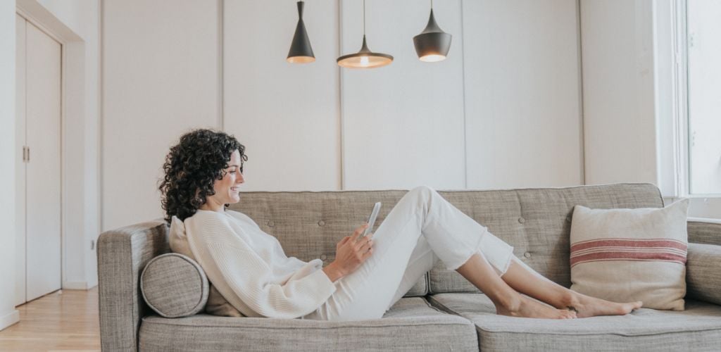 Woman sitting on the sofa while using a tablet. 