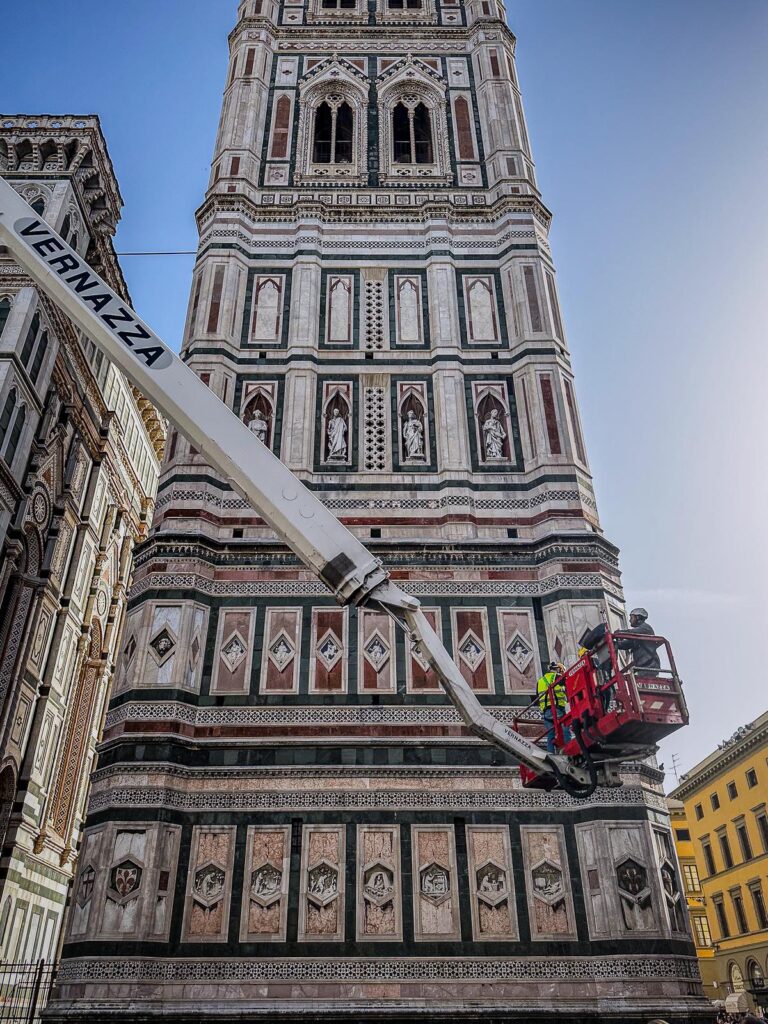 Maintenance work at Giotto's Bell Tower in Florence, Italy, showcasing historic conservation efforts with crane operation and intricate marble architecture.