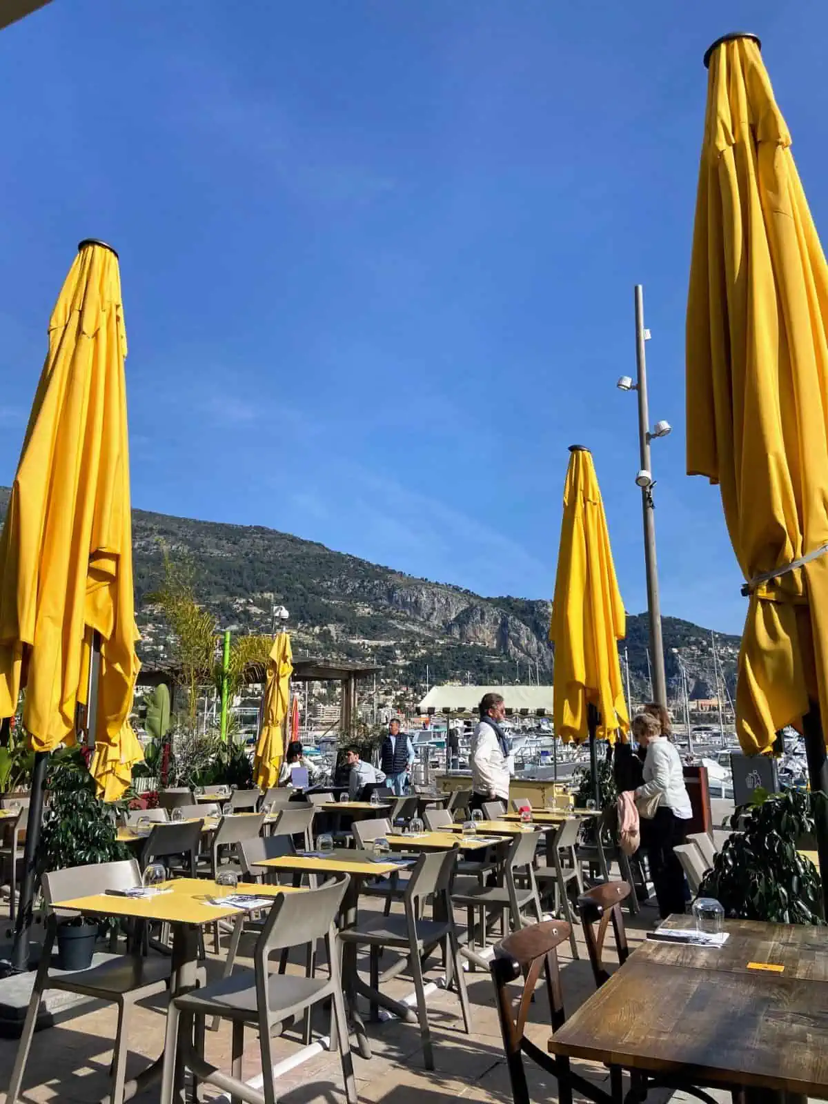 Tables and umbrellas on the patio of a pizza restaurant in Menton