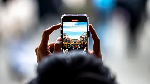 Getty Images A person uses a mobile phone to film the shopping street at Asakusa district near Sensoji Temple, a popular tourist location, in Tokyo on January 18, 2024 (Credit: Getty Images)