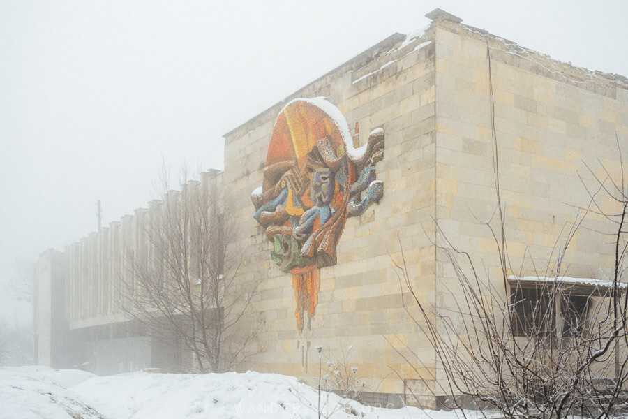 An abandoned House of Culture in Tianeti, Georgia, with a modernist design and a mosaic emblem on one side.