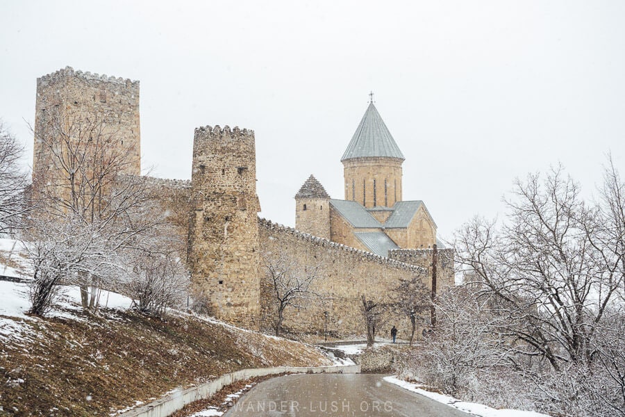 Ananuri Fortress complex on the Georgian Military Highway, with its stone walls, towers and church covered in winter snow.