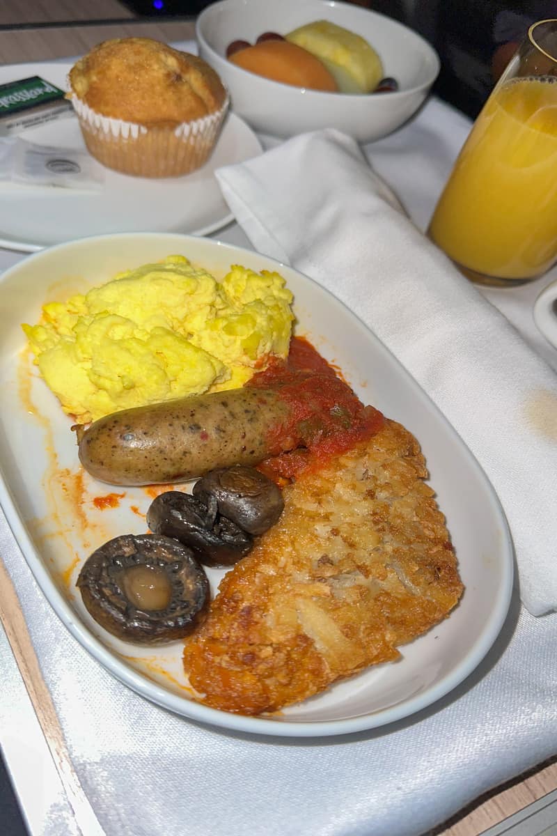 Breakfast of eggs, a muffin, sausage and OJ