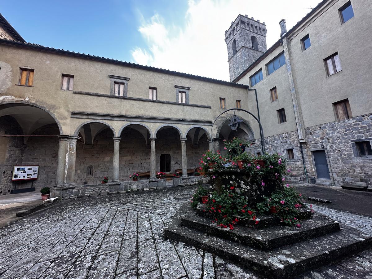 Abbey of San Salvatore tranquil courtyard with vibrant flowers, Tuscany Italy