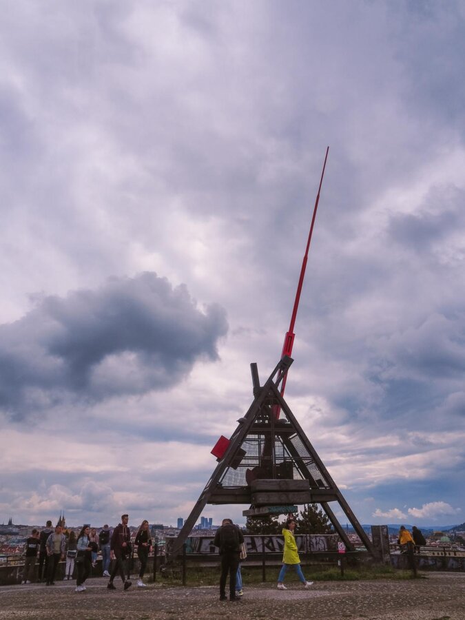 Visitors at Prague Metronome in Letná Park with cloudy skyline