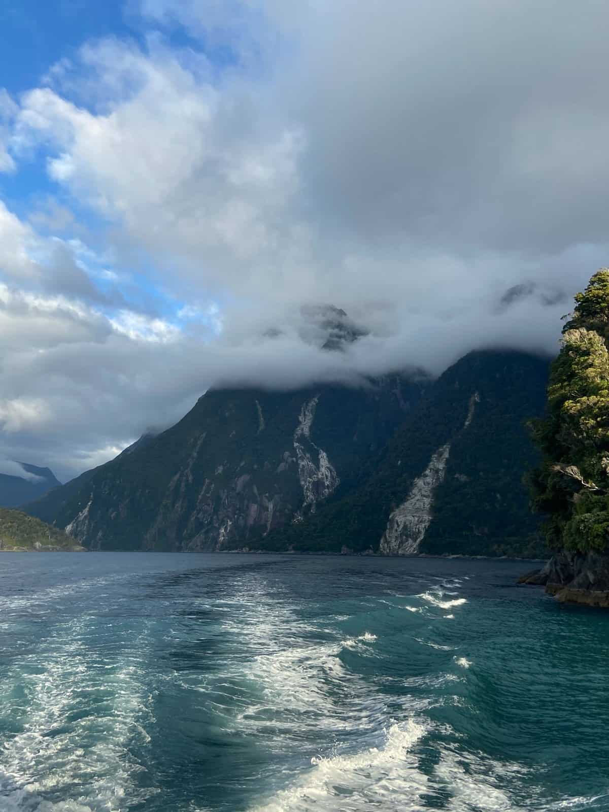 clouds coming over the mountains and water during a cruise in Milford Sound, NZ