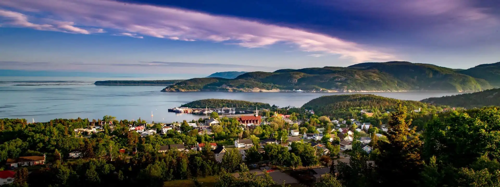 View over Tadoussac, Quebec, Canada with rolling hills, houses, green trees and water 