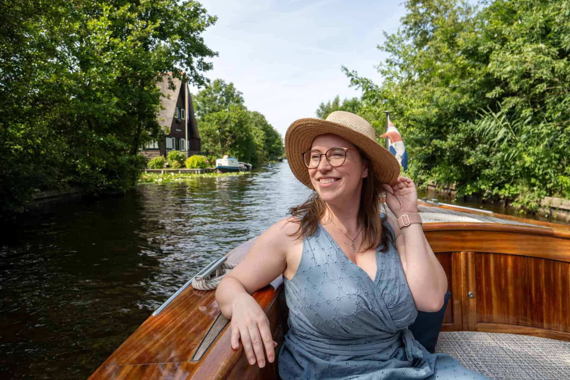 Jessica on a boat in Europe, touching her hand to her hat